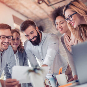 people standing over an office desk working together